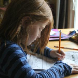 Girl drawing at a table with a pencil